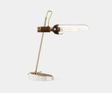Emerson: Sculptural Table Lamp in Gold-Plated Brass, Marble & Glass. The Emerson table lamp by Mezzo Collection stuns with its sculptural silhouette. This modern masterpiece features a gleaming gold-plated brass body, a sleek glass enclosure, and a luxurious Carrara marble base, casting a captivating glow in any modern living space.
