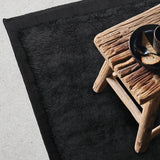 Fez Rug in Noir with a wooden stool, showing the border