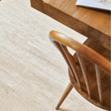Glam Rug in Perle, close up beneath a wooden dining chair