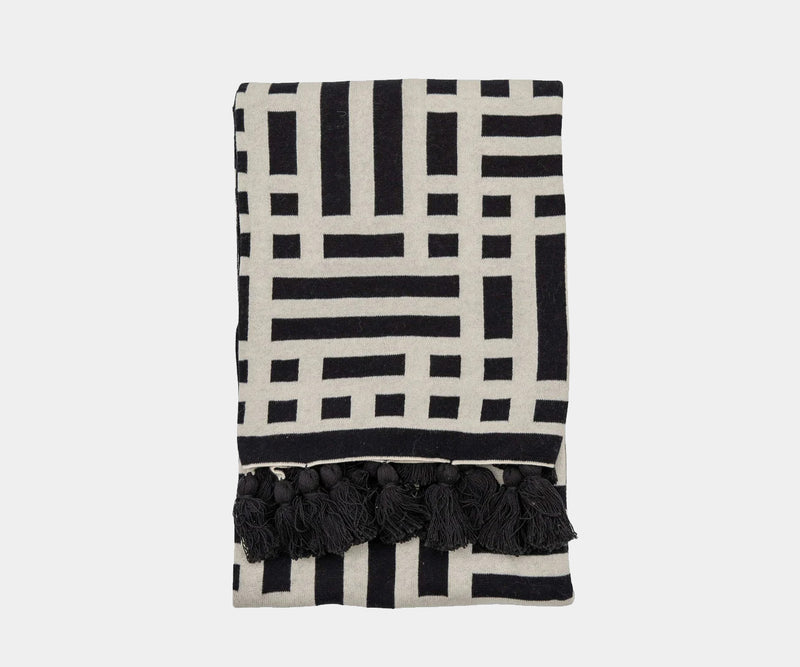 Textured Luxe: Black & Cream Modern Knit Throw with Tassels. This luxuriously textured, black and cream knit throw with charming tassels adds a touch of modern elegance to any living space.