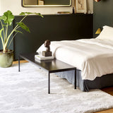 Délice Rug in Silver at the foot of a bed