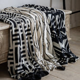 Modern Minimalism Meets Comfort: Black & Cream Knit Throw with Tassels. This stylish black and cream knit throw with tassels complements any modern minimalist space. Drape it over your favorite armchair for a touch of contemporary luxury.